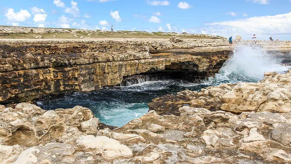 Arco de piedra caliza del Devil's Bridge con olas rompiendo debajo