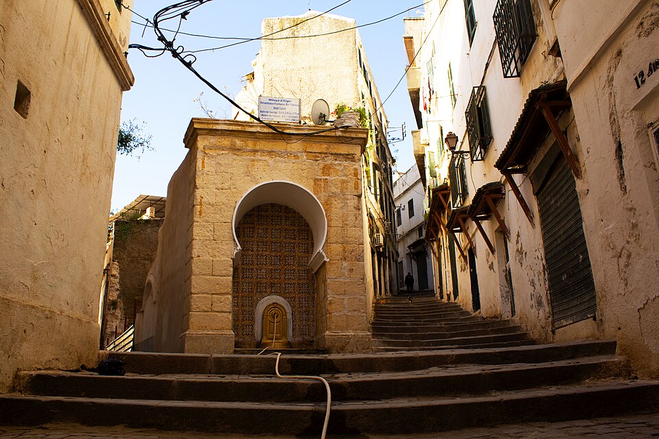 Fuente de piedra con arco al pie de una escalera en la Casbah de Argel