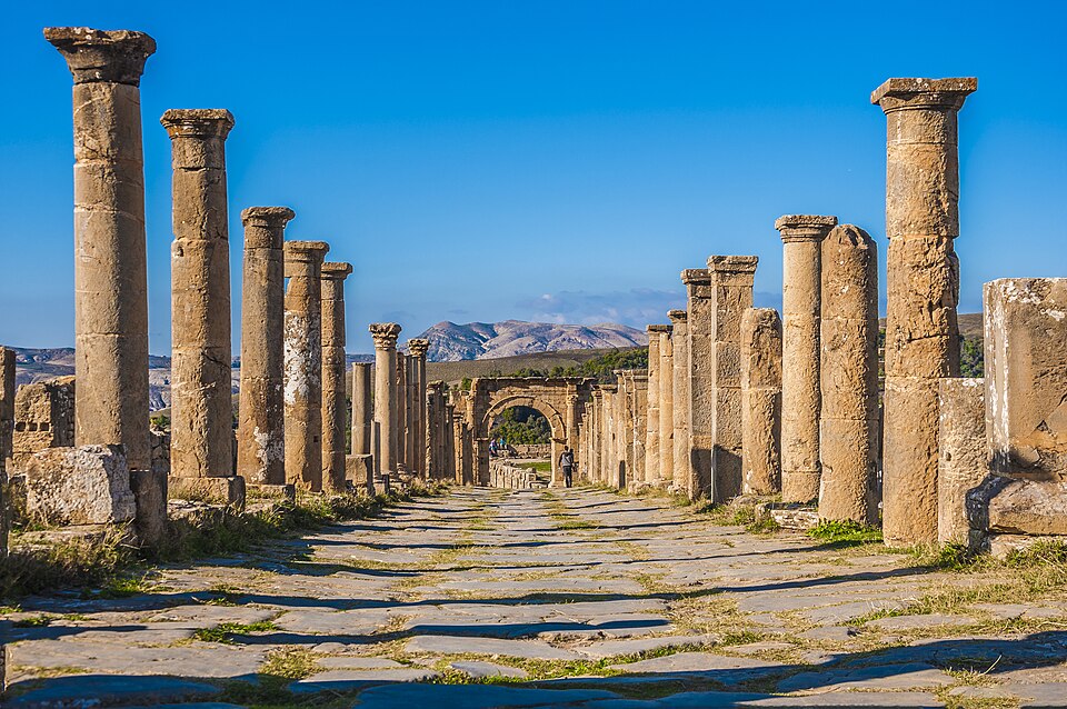 Calle con columnas romanas y un arco al fondo en Djémila