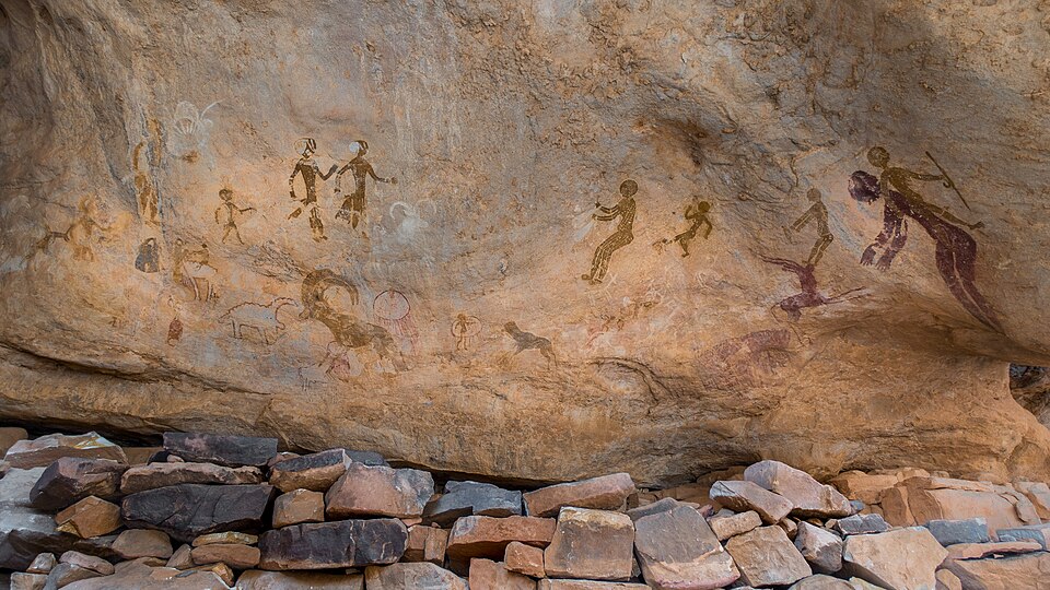 Pinturas rupestres de figuras humanas y animales bajo una roca en el Tassili n'Ajjer