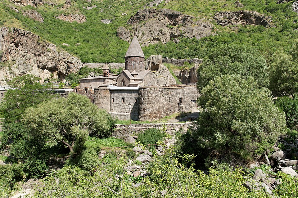 El monasterio de Geghard entre árboles y rocas en un valle verde