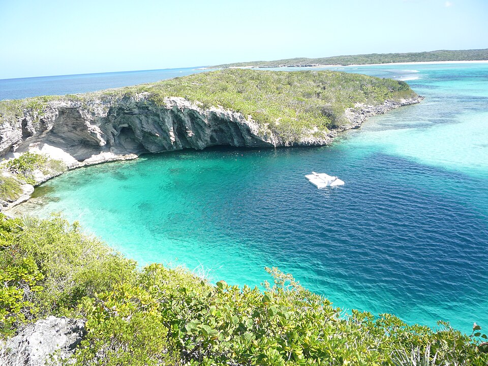 El círculo azul oscuro de Dean's Blue Hole en una bahía turquesa entre acantilados