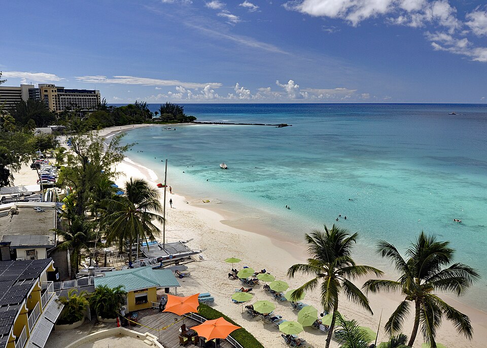 Playa de Carlisle Bay con agua turquesa, palmeras y sombrillas