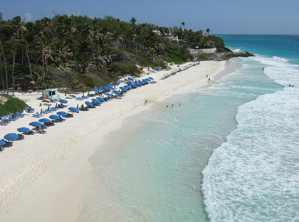 Playa de Crane Beach con arena blanca, sombrillas y olas turquesa