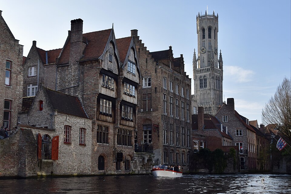 Un canal de Brujas con casas antiguas y el campanario detrás