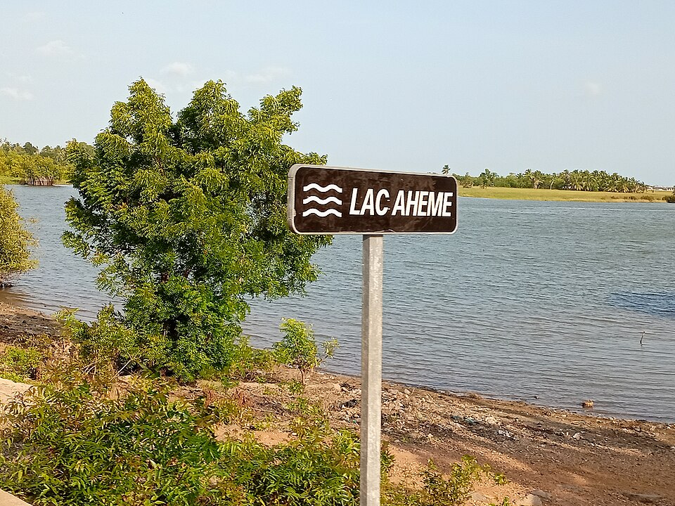 Orilla del lago Ahémé con un letrero y vegetación