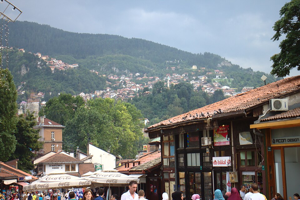 Calles del bazar Baščaršija con colinas de Sarajevo detrás