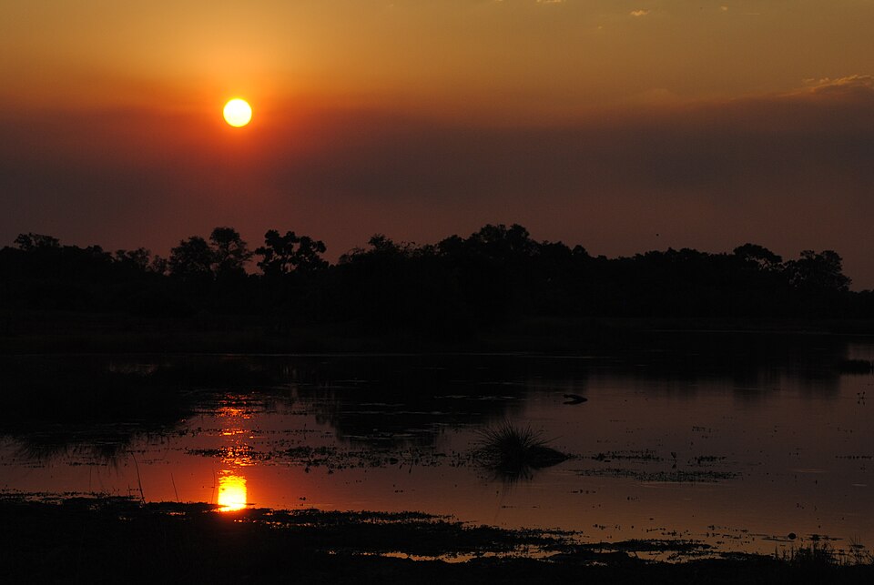 Atardecer naranja reflejado en una laguna de la reserva de Moremi