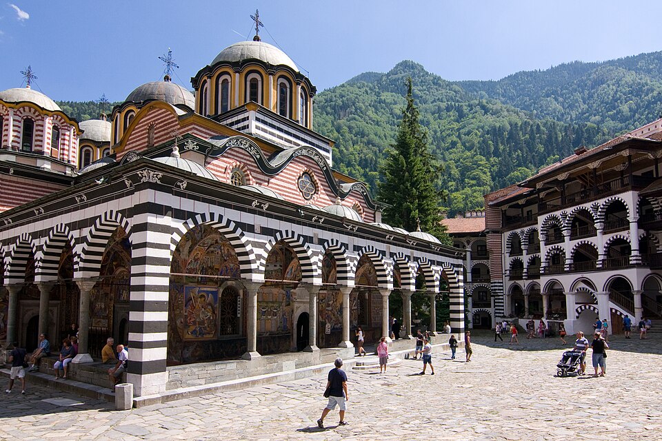 La iglesia del monasterio de Rila con arcos de rayas y montañas detrás