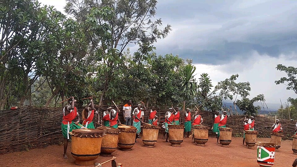 Tamborileros vestidos de rojo, blanco y verde tocando en semicírculo en Gishora
