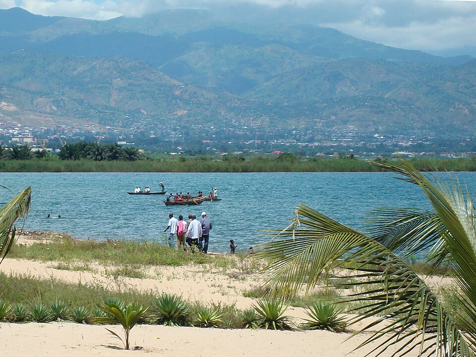 Playa con palmeras junto al lago Tanganica, con Bujumbura y las montañas al fondo