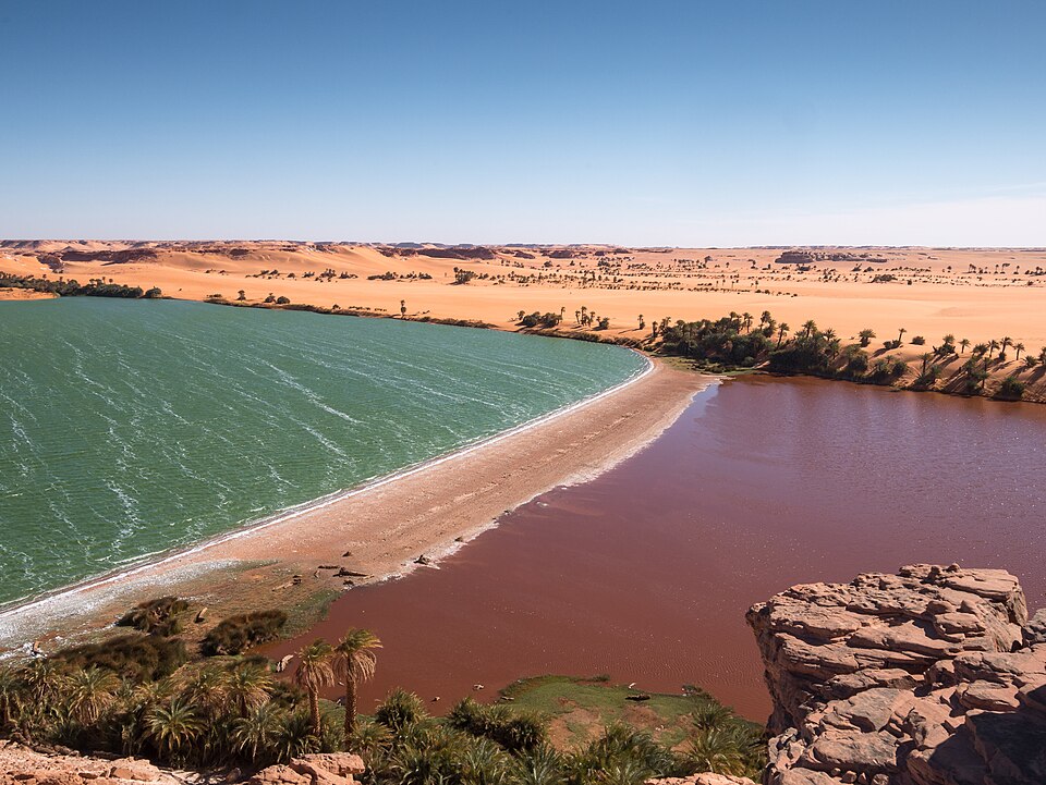 Lago Yoa con aguas verdes y rojizas rodeado de desierto en Ounianga