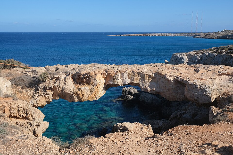 Un puente natural de roca sobre agua azul en el cabo Greco