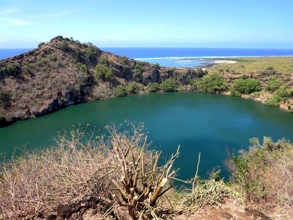 Lago salado de color verde dentro de un cráter junto al mar
