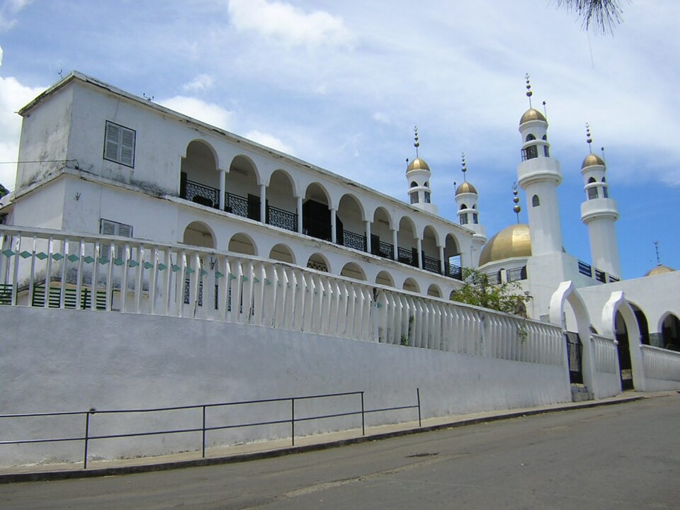 Mezquita blanca con arcos, minaretes y cúpula dorada en Moroni