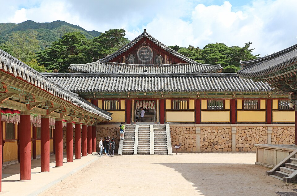 Un patio del templo Bulguksa con edificios de madera pintada y montañas