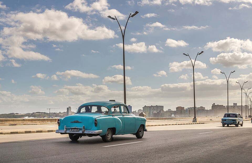 Un coche antiguo azul por la avenida del Malecón de La Habana