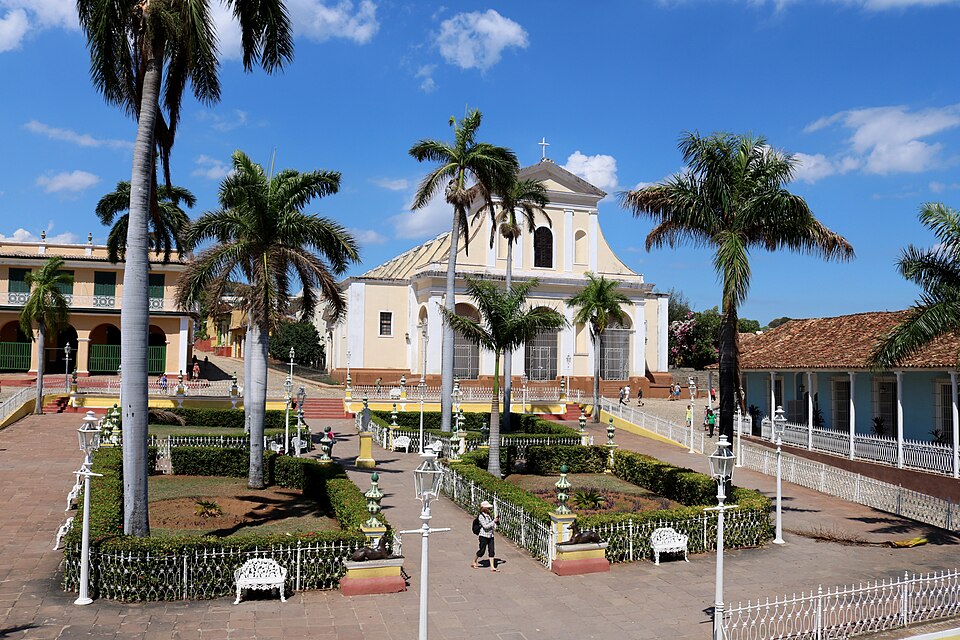 La Plaza Mayor de Trinidad con palmeras, jardines y la iglesia al fondo