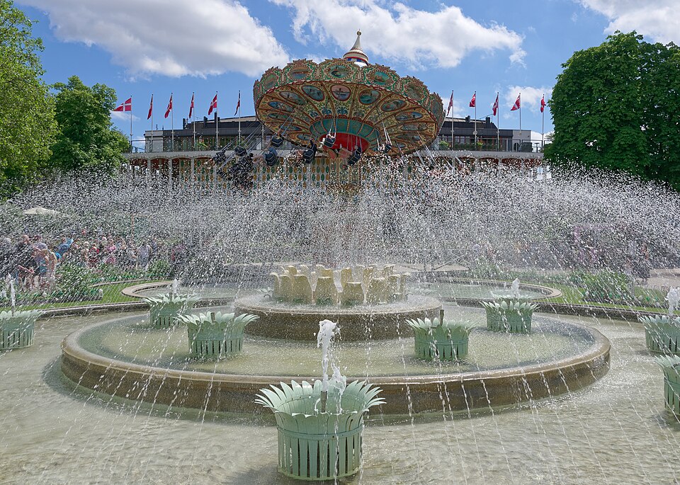 Una fuente frente a un juego mecánico en los Jardines de Tivoli