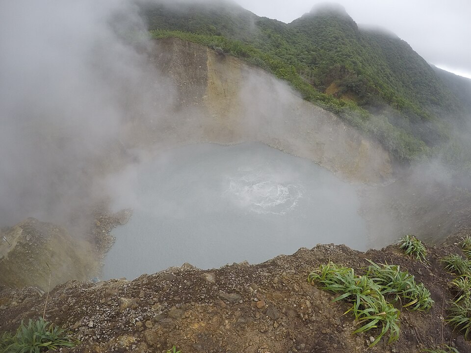 El Boiling Lake echando vapor dentro de un cráter rodeado de vegetación