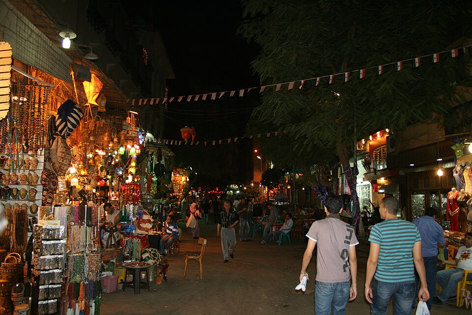 Calle del bazar de Jan el-Jalili de noche, con tiendas iluminadas y gente paseando