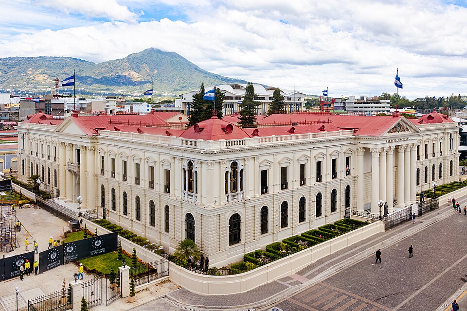 El Palacio Nacional de San Salvador, blanco con techos rojos, con el volcán de San Salvador detrás
