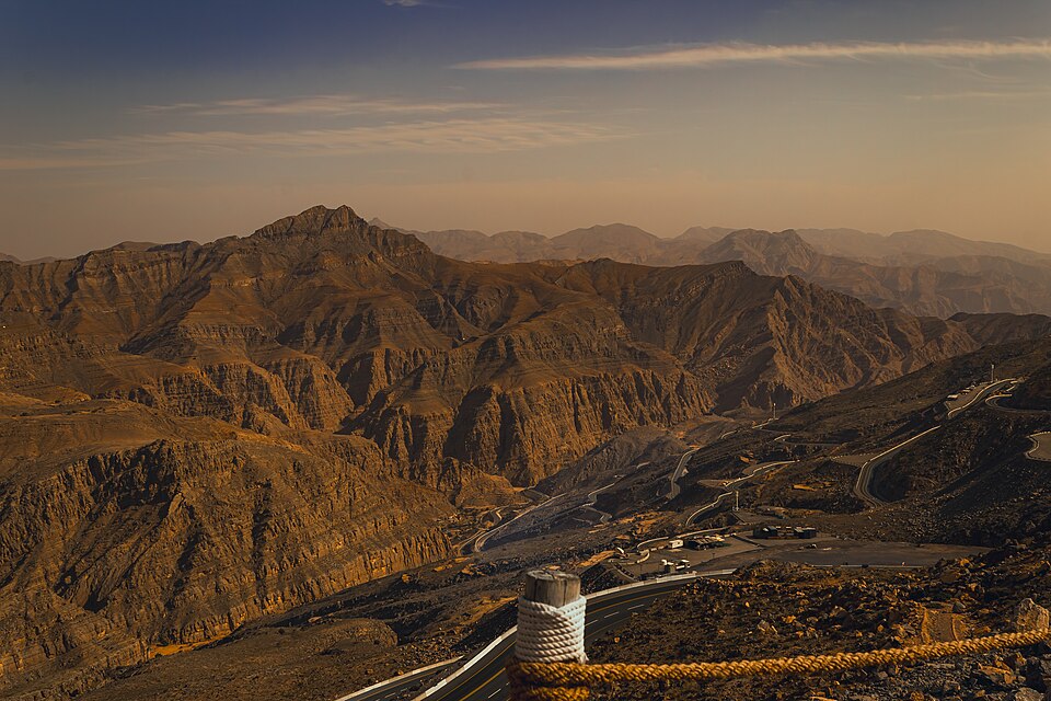 Montañas áridas de Jebel Jais al atardecer con una carretera de curvas