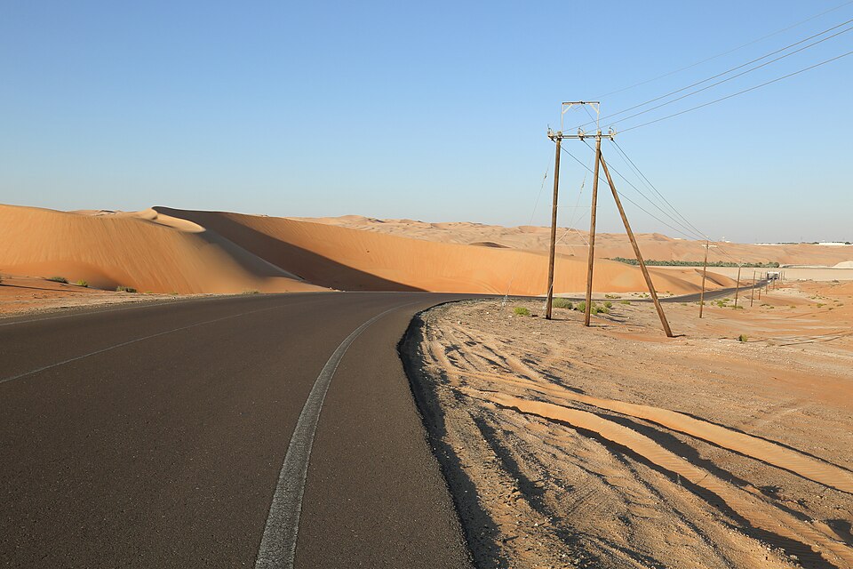 Una gran duna anaranjada junto a una carretera en el desierto de Liwa
