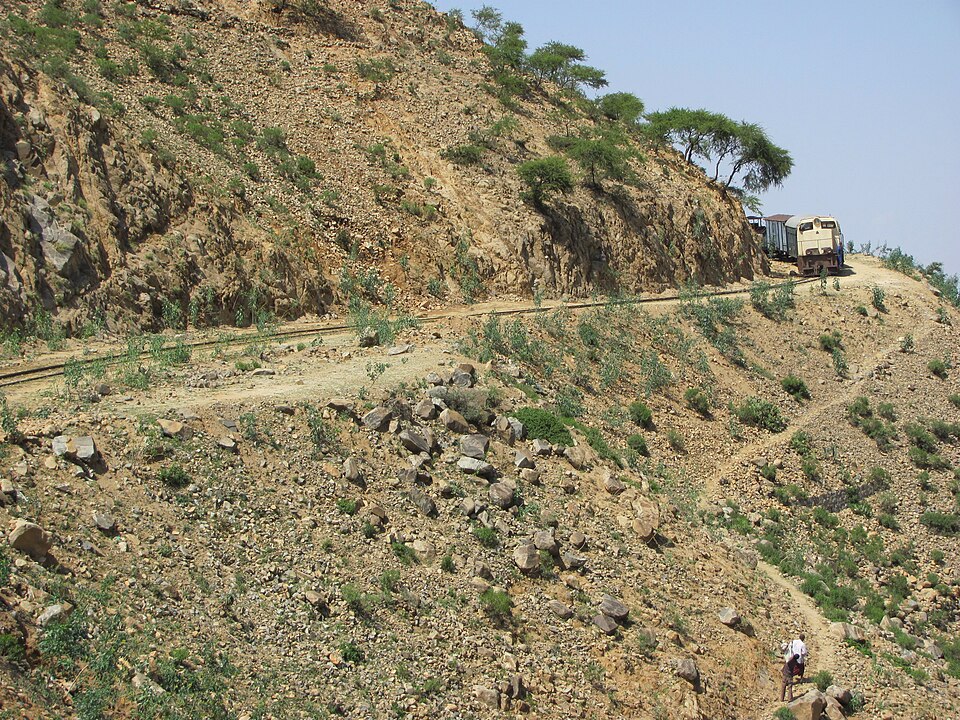 Vía de tren en una ladera de montaña con un vagón en la curva