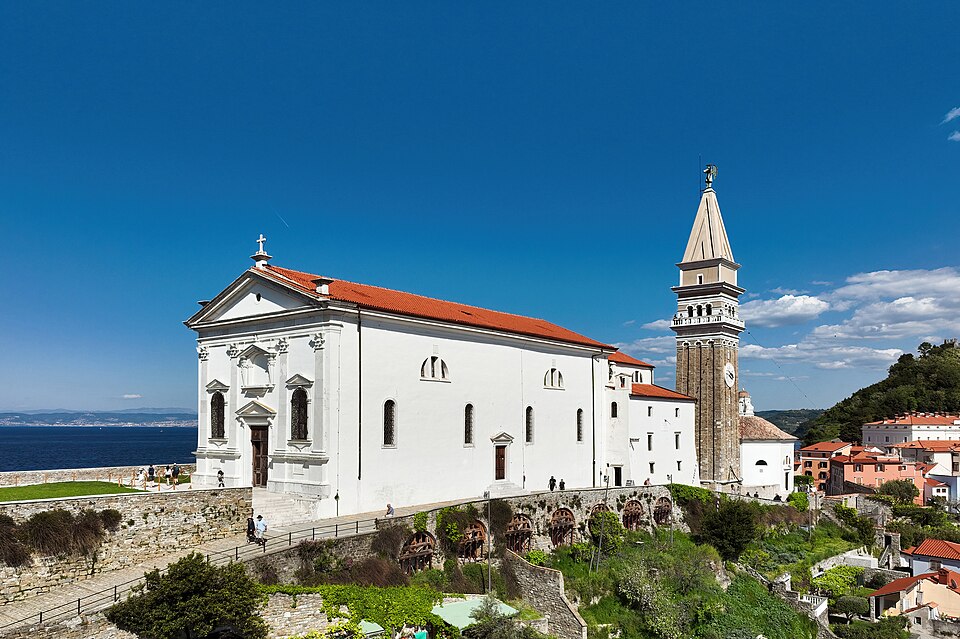 La iglesia de San Jorge en Piran con su campanario y el mar detrás