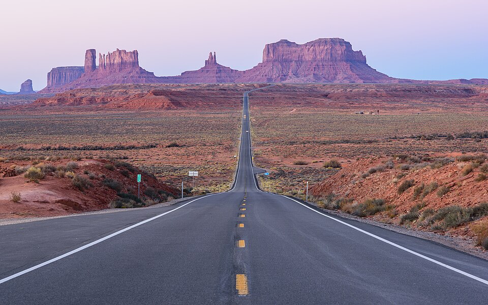 Carretera recta hacia las torres de roca roja de Monument Valley