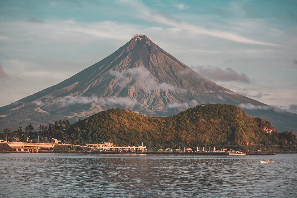 El volcán Mayon de cono perfecto sobre una colina verde y el mar