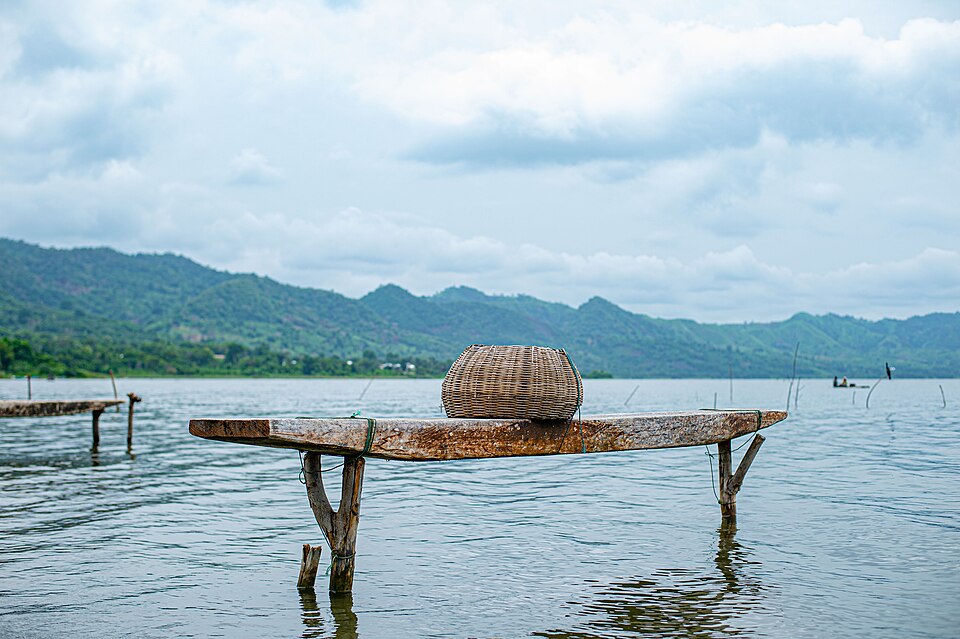 Tabla de pesca con una canasta sobre el agua del lago Bosomtwe y colinas al fondo