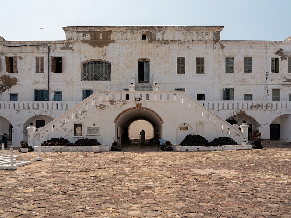 Patio y fachada blanca del castillo de Cape Coast con su escalinata