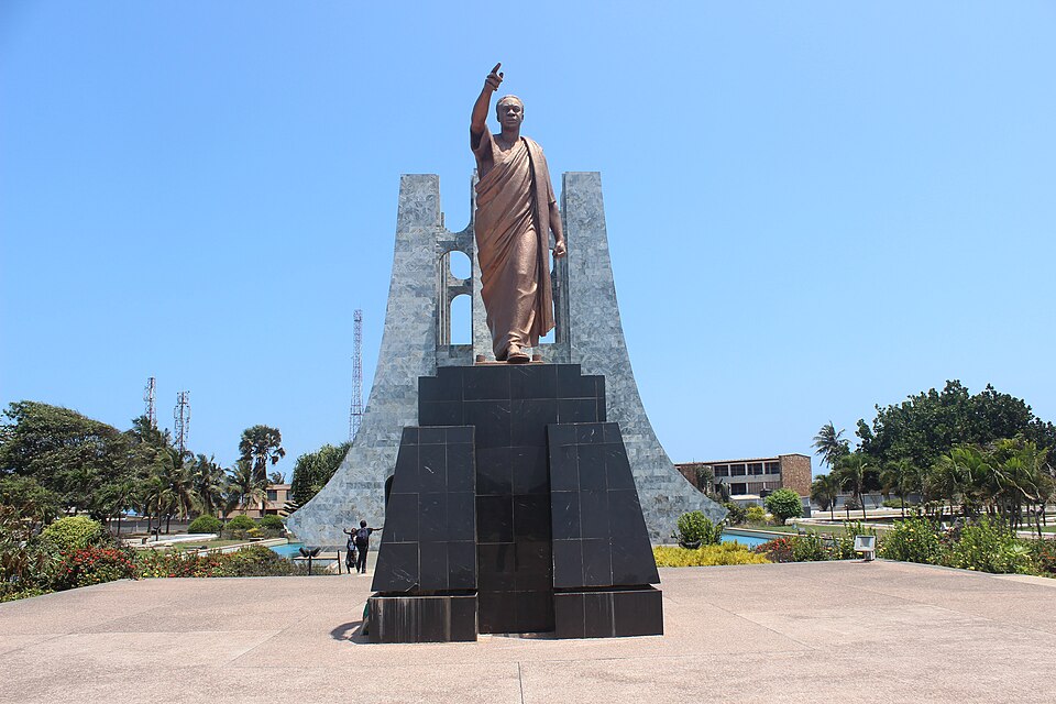 Estatua de bronce de Kwame Nkrumah con el brazo en alto frente al mausoleo