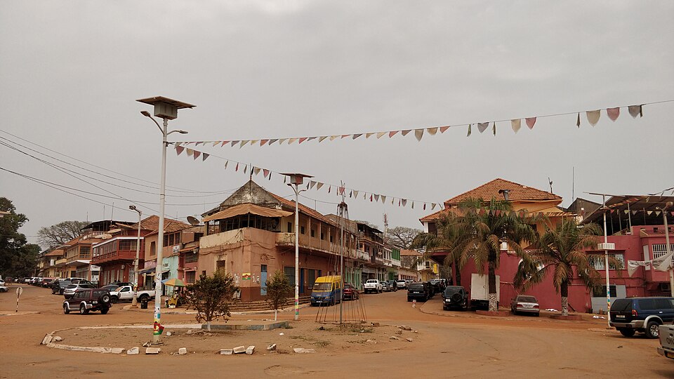 Calle del barrio antiguo de Bisáu con casas coloniales y banderines