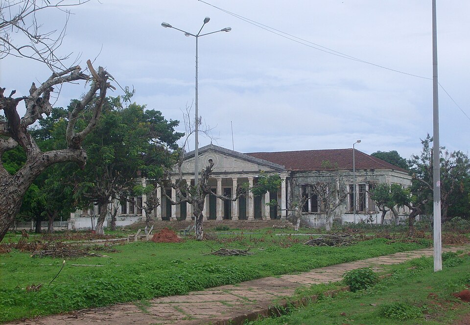 Edificio colonial con columnas abandonado en Bolama, rodeado de árboles