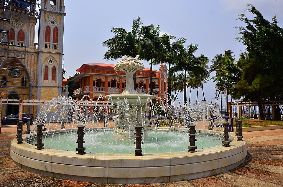 Plaza con fuente y palmeras frente a un edificio colonial en Malabo