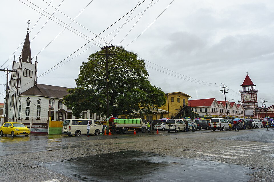 Calle de Georgetown con una iglesia blanca y, al fondo, la torre del reloj del mercado Stabroek