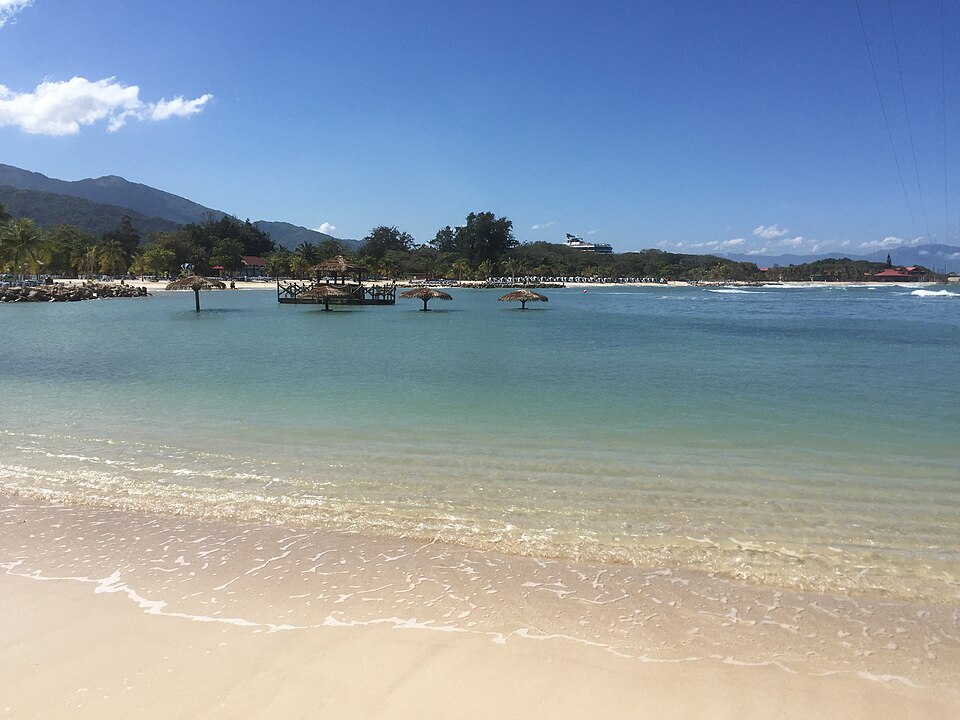 Playa de arena blanca y agua turquesa en Labadee con montañas al fondo