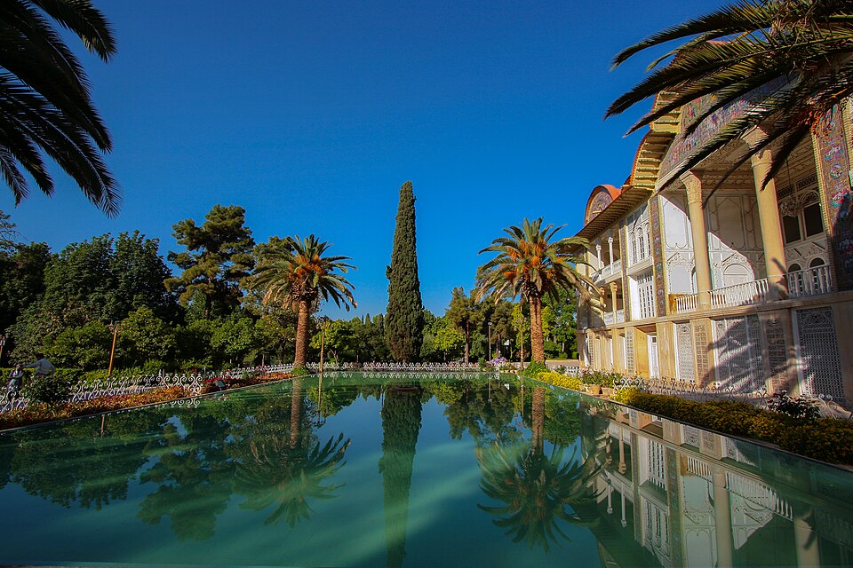 El palacio del jardín de Eram reflejado en un estanque entre palmeras