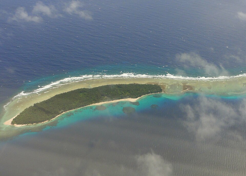 Un islote verde rodeado de arrecife visto desde el aire
