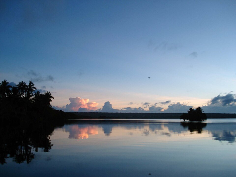 El lago Tegano al atardecer con palmeras reflejadas en el agua