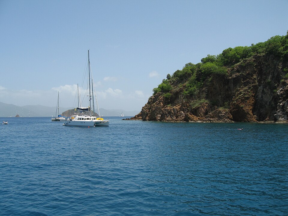 Acantilados de la isla Norman sobre las cuevas de Treasure Point con un velero cerca