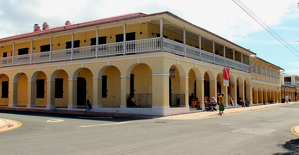 Edificio colonial amarillo con arcadas y balcones en Frederiksted
