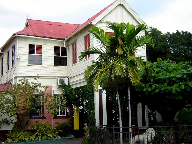 La casa blanca de madera del Museo de Bob Marley con techo rojo y palmeras