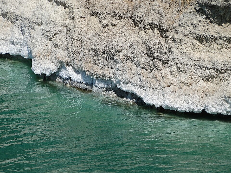 Orilla de cristales de sal blanca junto al agua verde del mar Muerto