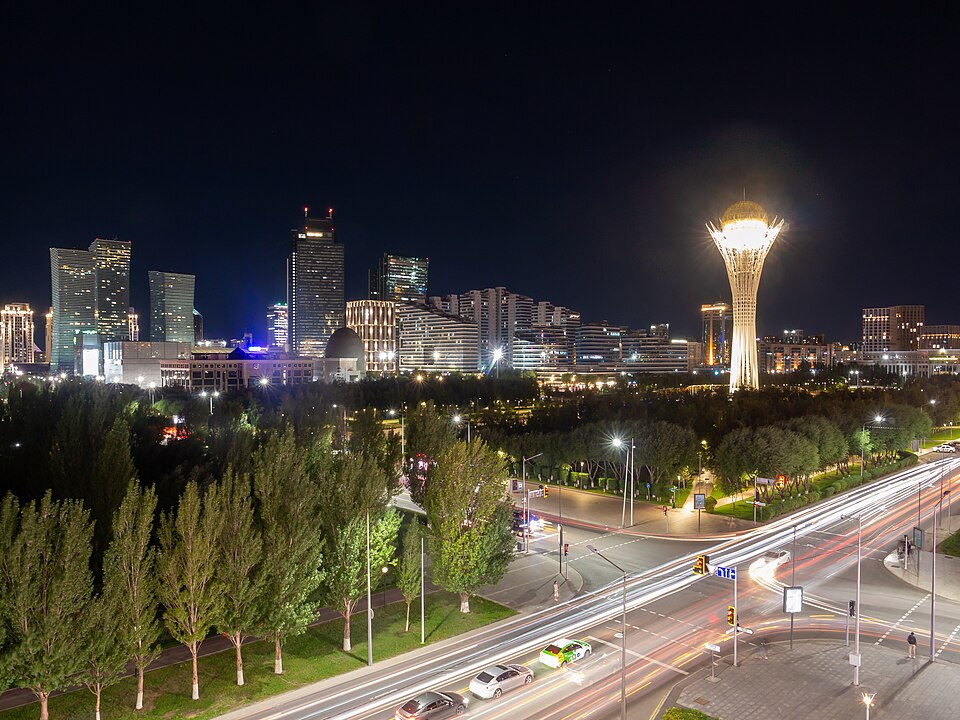 La torre Baiterek iluminada entre rascacielos de Astaná de noche