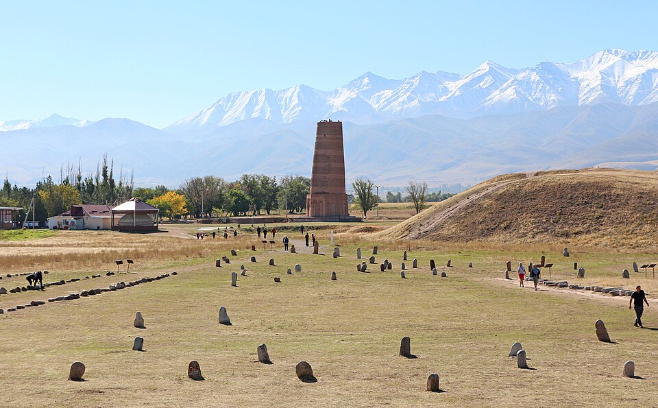 La torre de Burana con lápidas de piedra y montañas nevadas
