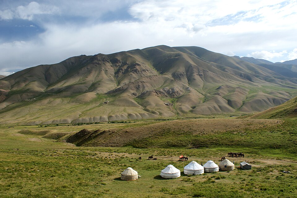 Un campamento de yurtas blancas en los pastos verdes de Song-Kol